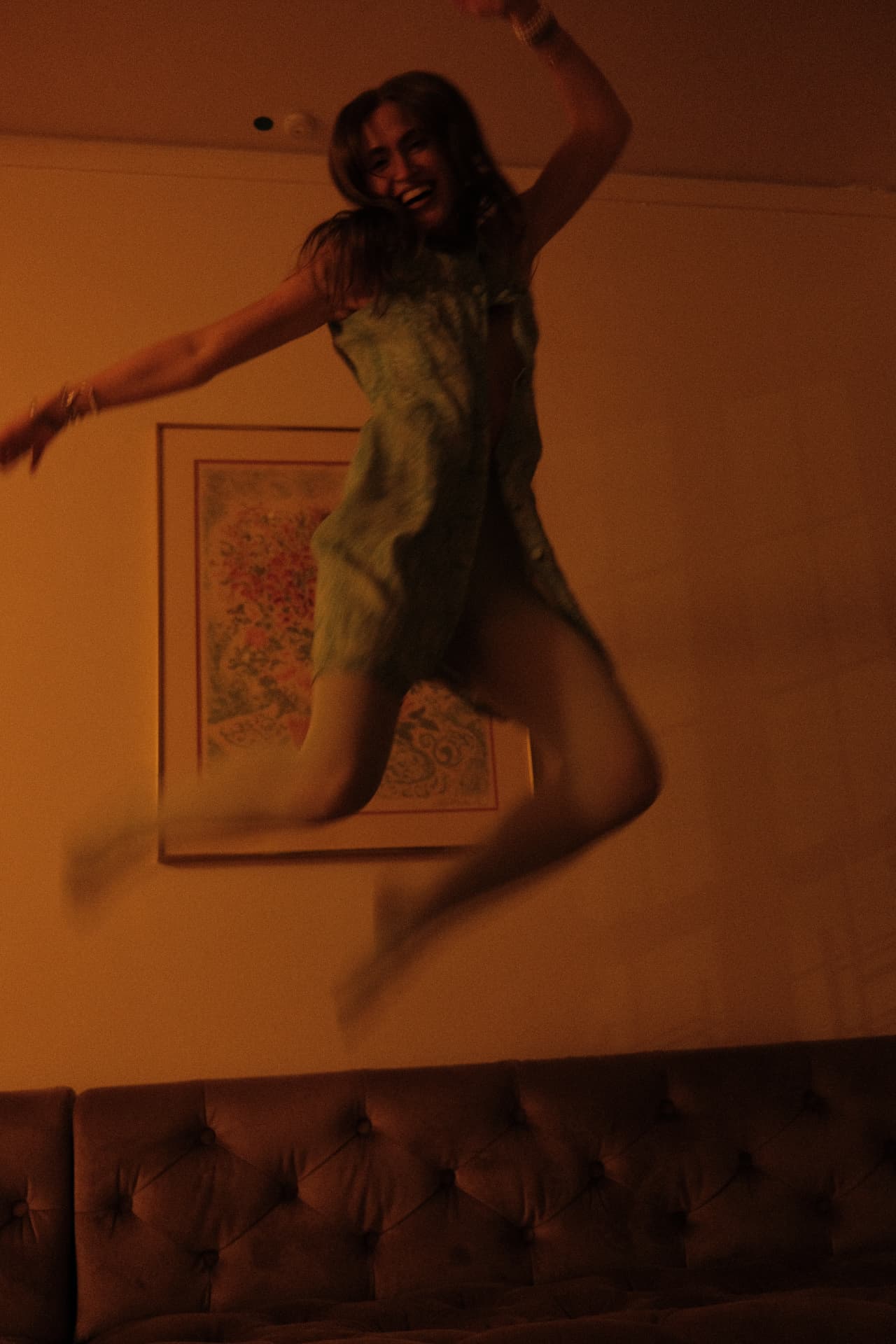 Rachel mid-leap in a green printed mini dress