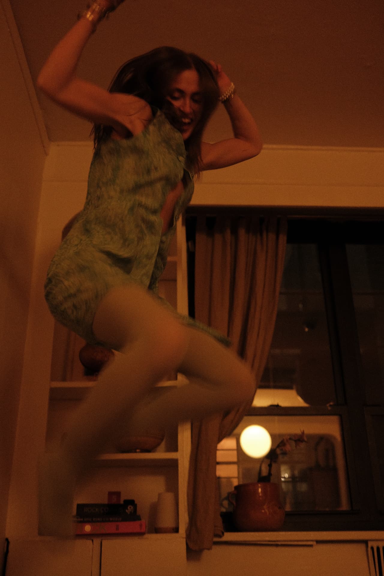 Rachel jumping in a green printed mini dress